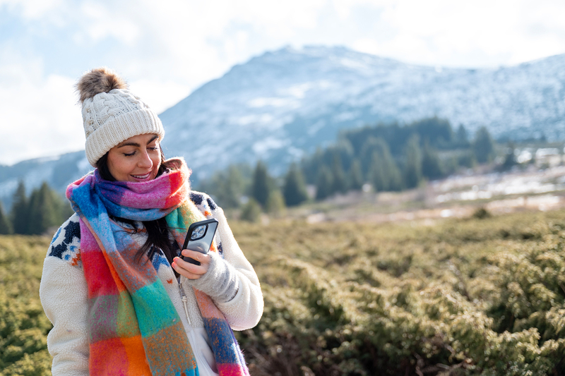 Kobieta z telefonem w ręku na tle gór.