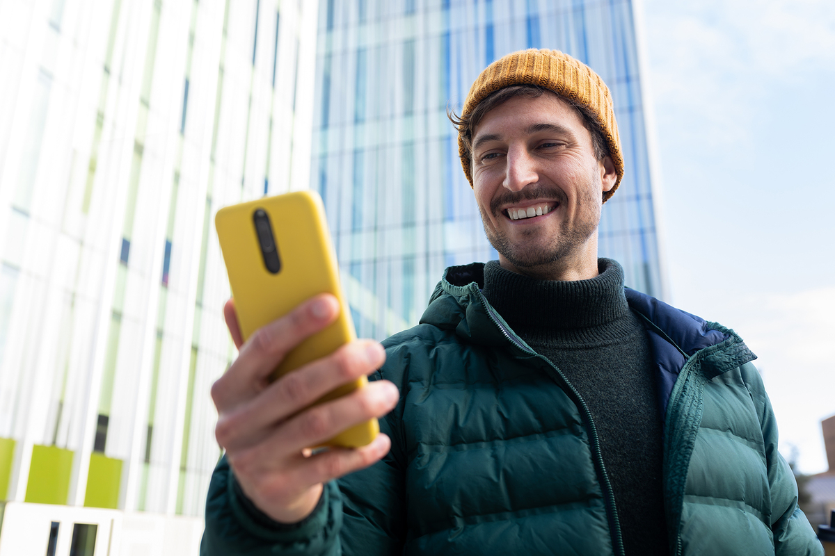 Mężczyzna z telefonem w ręku na tle wieżowców.