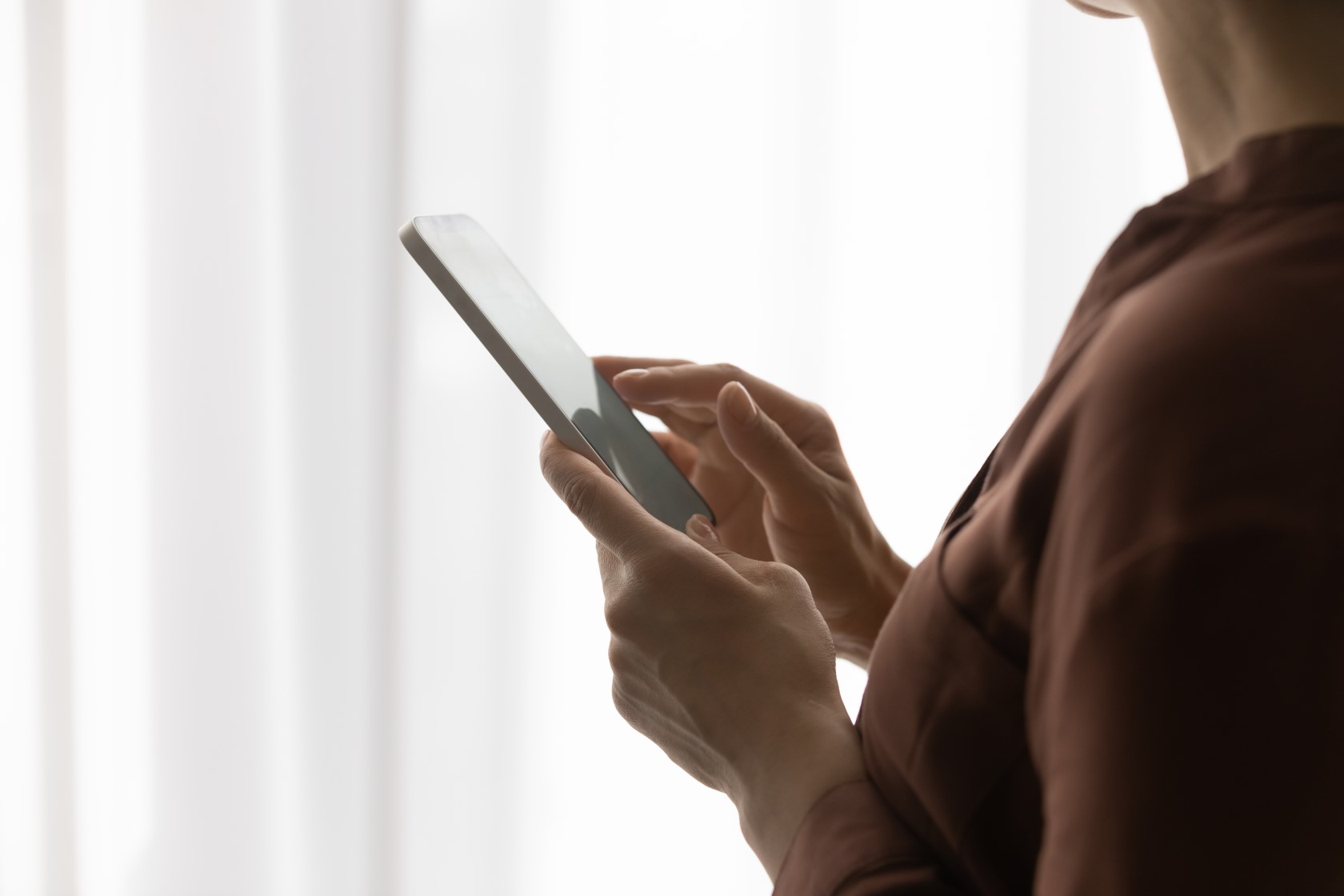 Kobieta przy oknie trzyma telefon