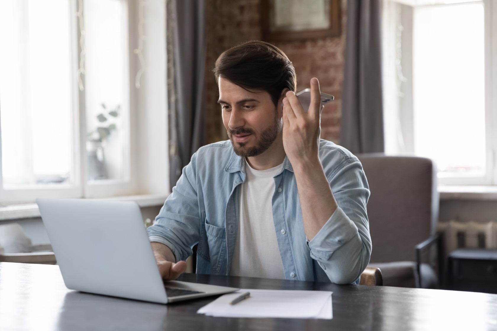 Mężczyzna przed laptopem rozmawia przez telefon