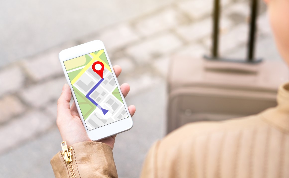 Kobieta trzyma telefon z mapą wskazującą punkt docelowy