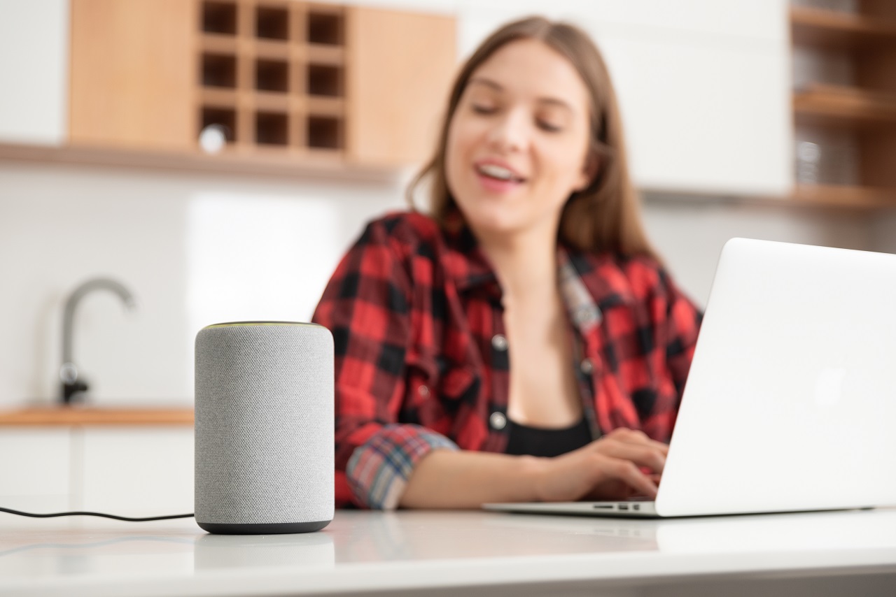 Młoda kobieta korzysta z komputera i rozmawia z asystentem głosowym Alexa