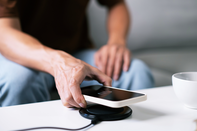 Mężczyzna kładzie telefon na ładowarce.