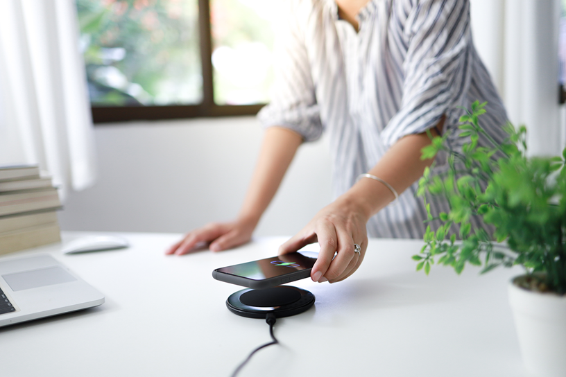 Kobieta kładzie telefon na ładowarce indukcyjnej.