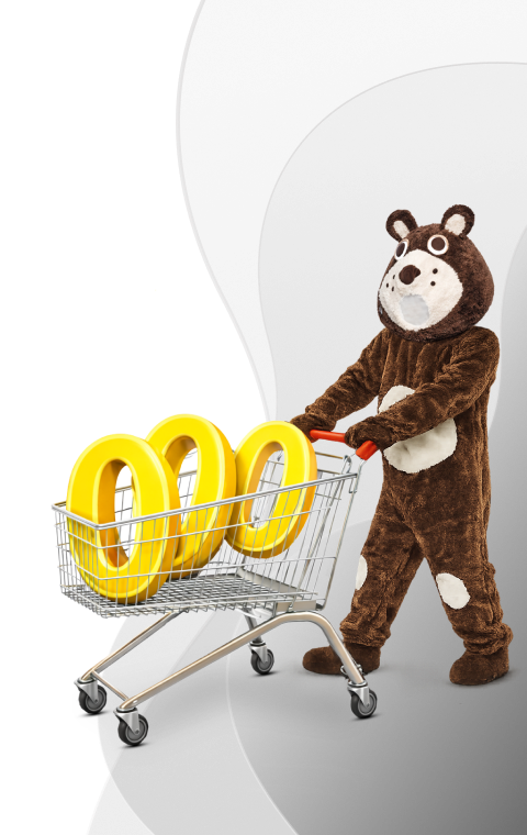 Osoba w kostiumie misia pcha wózek sklepowy z żółtym napisem „000”, symbol promocji lub rabatu w sklepie