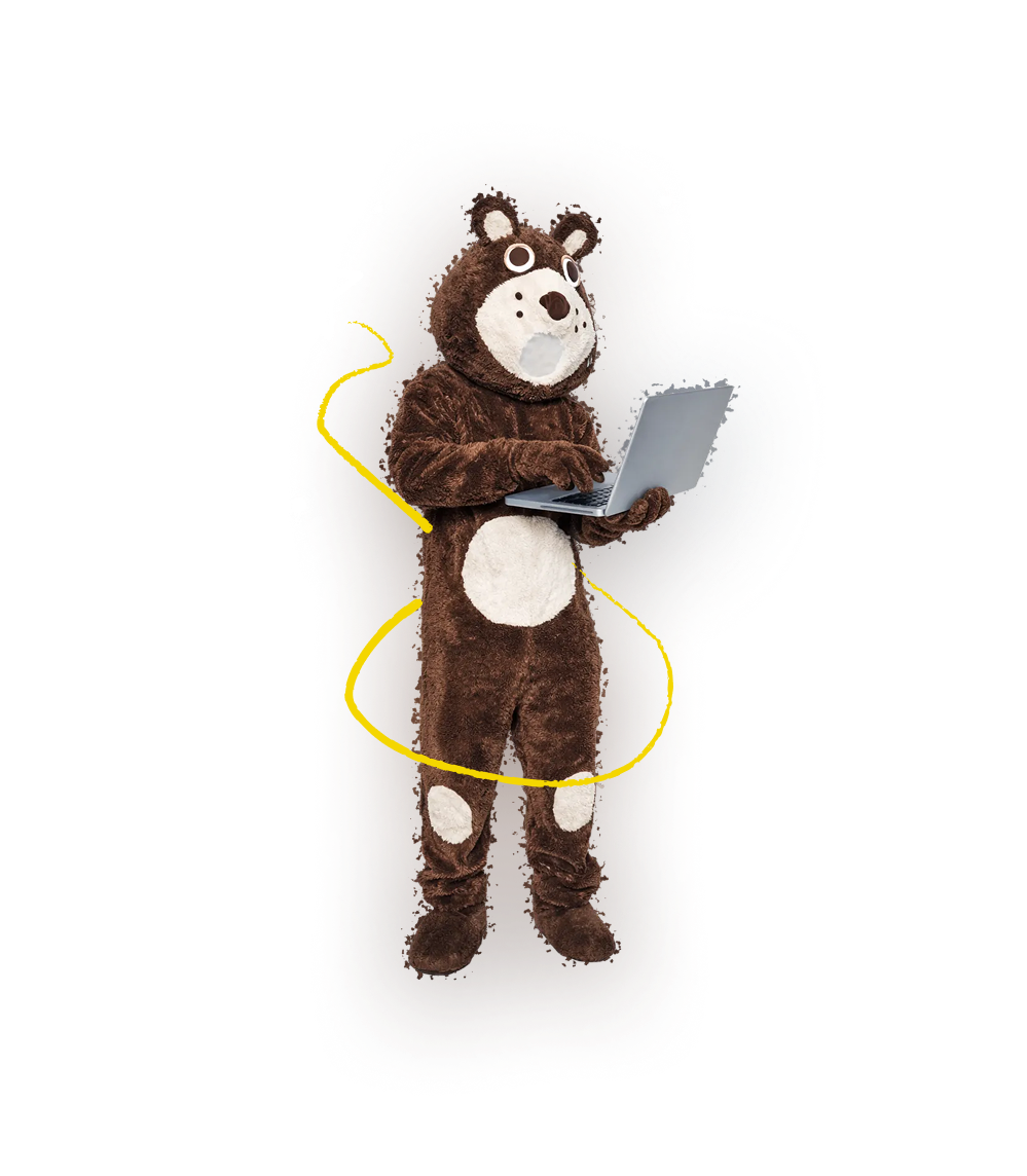 Maskotka niedźwiedzia pracująca na laptopie na białym tle